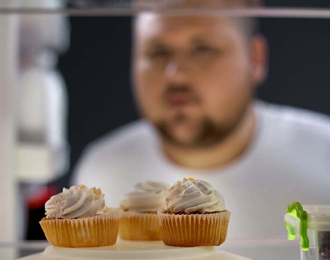 man looking at three cupcakes